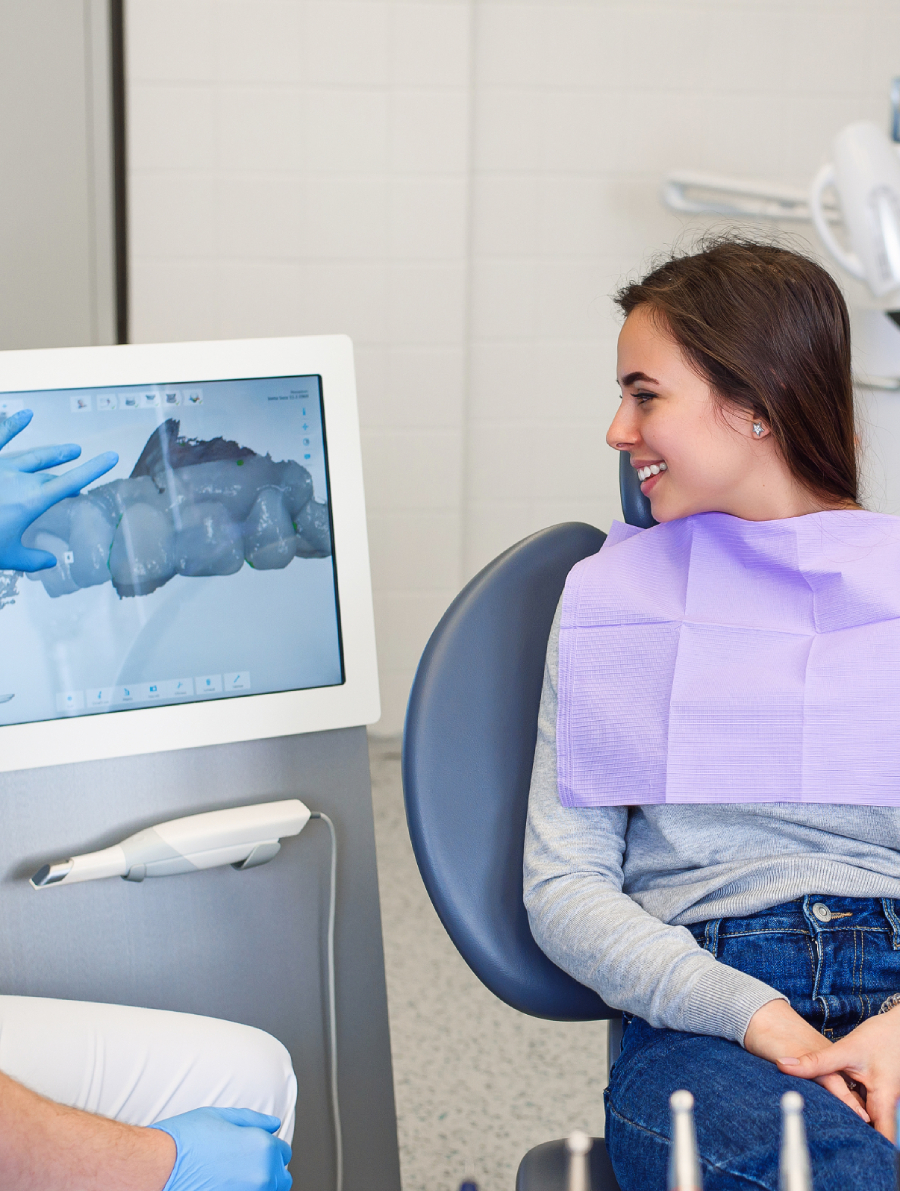 Woman looks at dental technology showing an xray of her teeth.