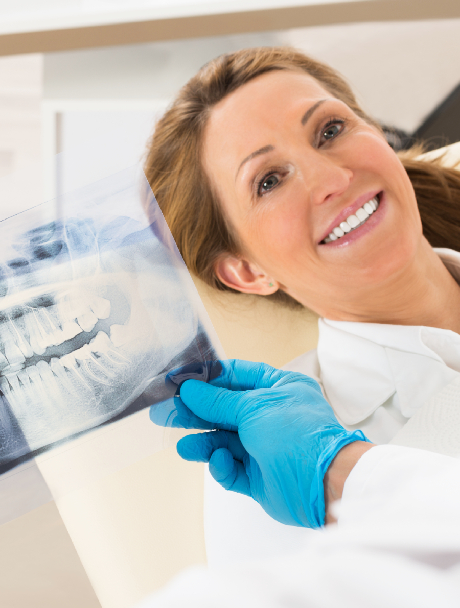 Woman smiles at the orthodontist as the orthodontist looks at her x-rays.